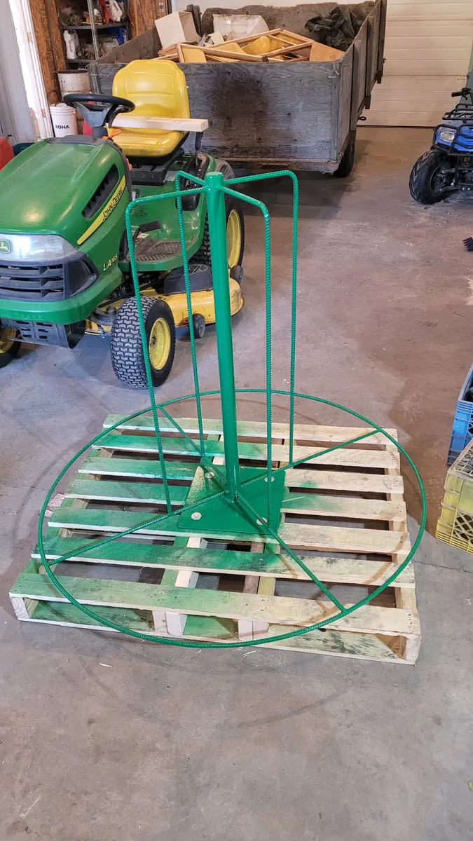Green powder-coated hose reel stand on a pallet in the shop
